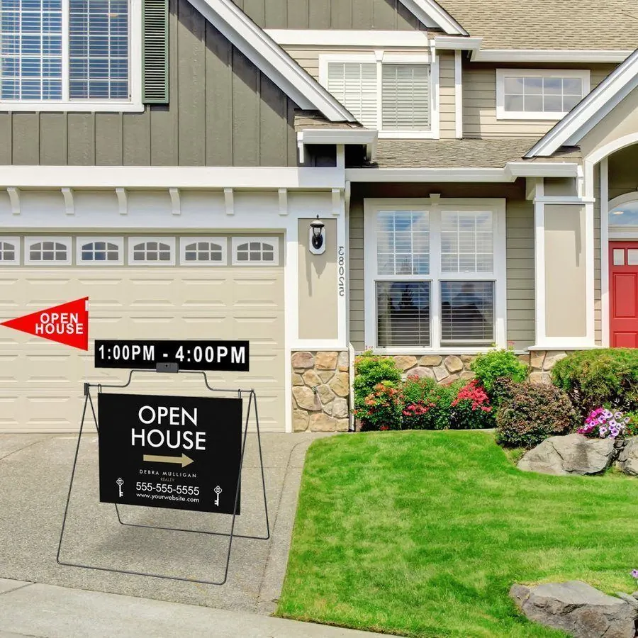 Black steel A-frame open house sign with rider and red pennant flag on a driveway in front of a house